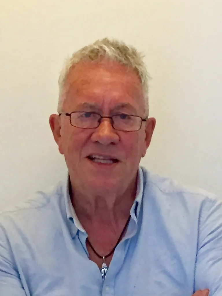 A photo of Chris Peters, the main guide for the private walking Tours of Oxford. In the image Chris is sat smiling and looking at the camera.