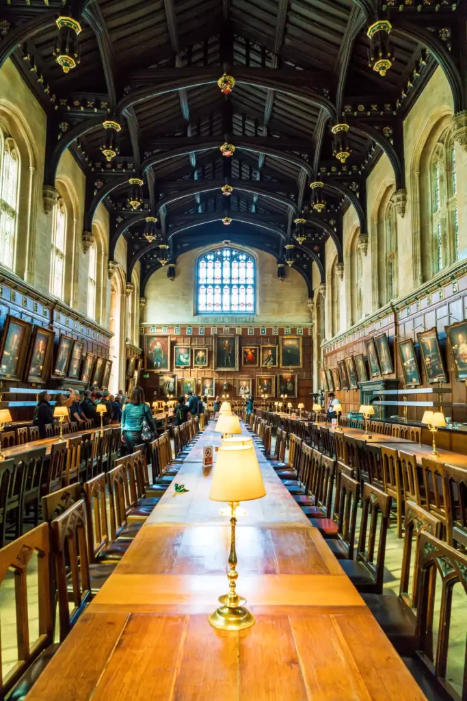 The hall at University College Oxford where there is a private walking tour taking place. The hall is lined by artwork and paintings.